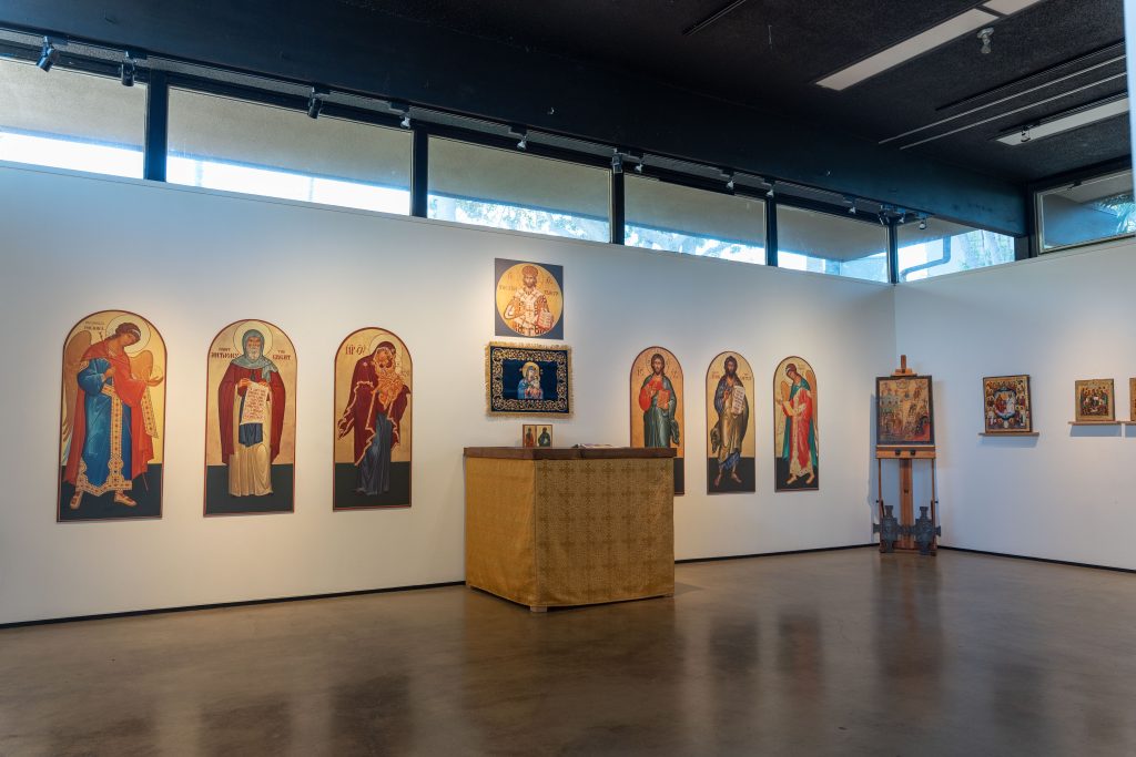 This image shows a diagonal view of the inside of an art gallery with religious icon paintings hung on the wall.