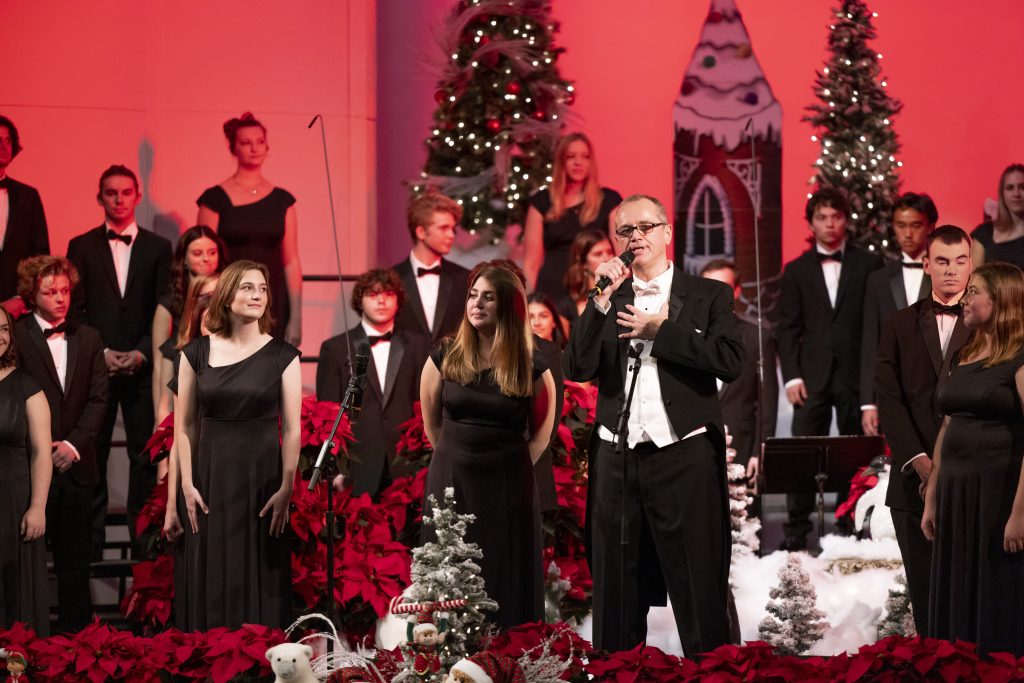 Dr. Dan Jackson speaks into the microphone during a PLNU Christmas music performance.