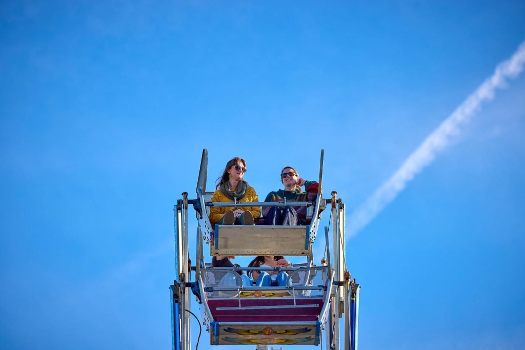Two friends ride in the cart of a Ferris Wheel at Homecoming.