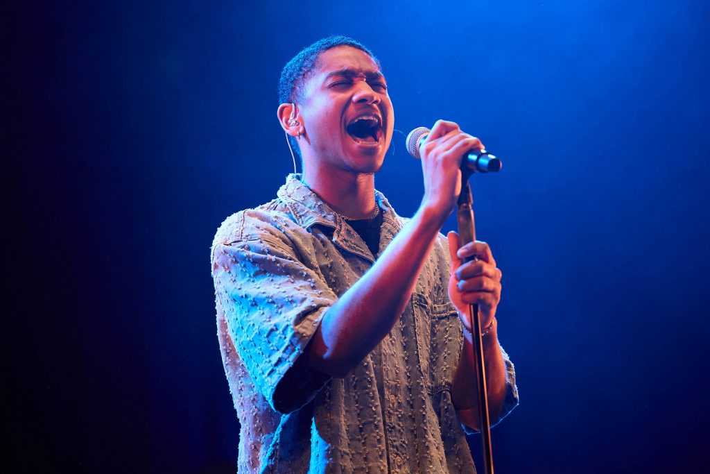 A PLNU singer emotionally sings into the microphone during a performance.
