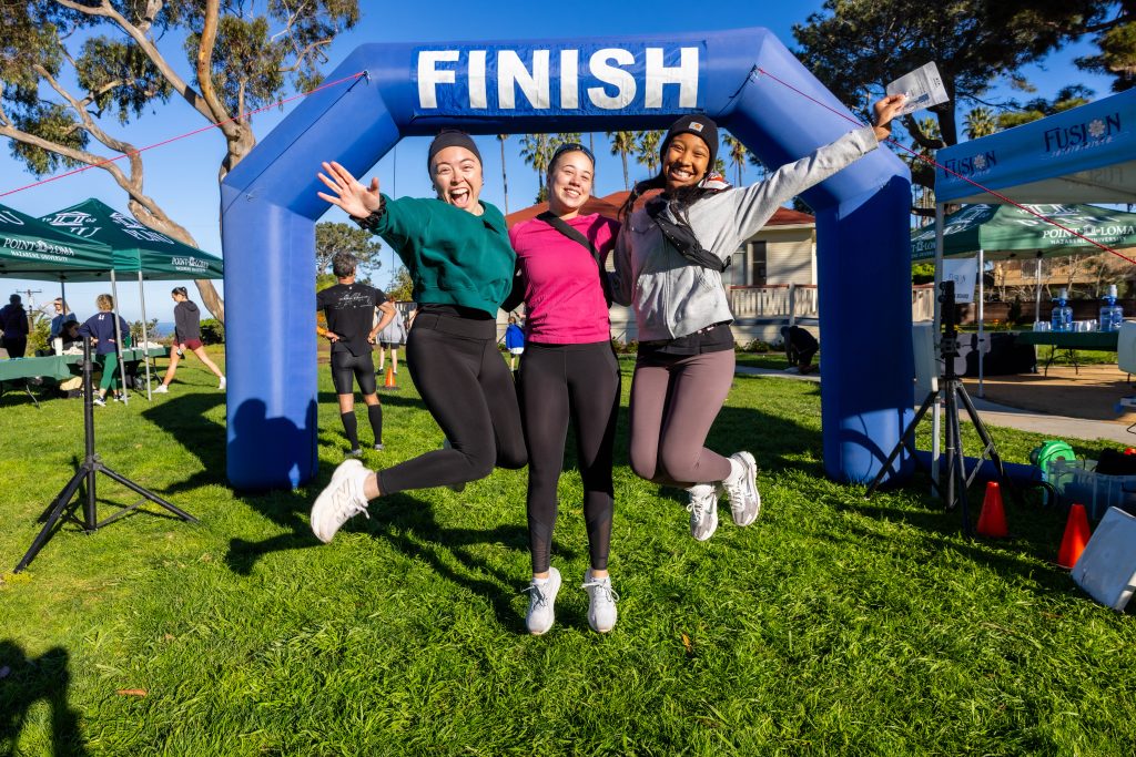 Three friends jump in synch at the finish line of the Homecoming 5K