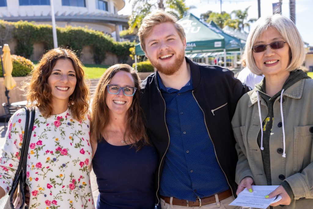 A group of friends reunite outdoors at PLNU Homecoming weekend.
