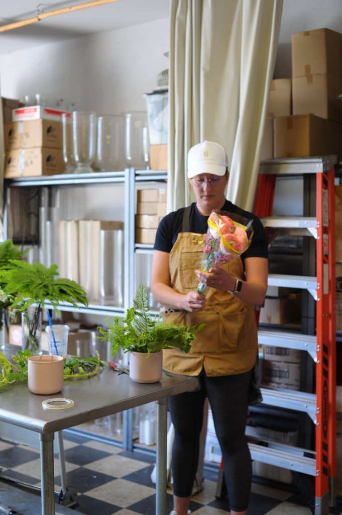 A PLNU student in her floral studio holding flowers.