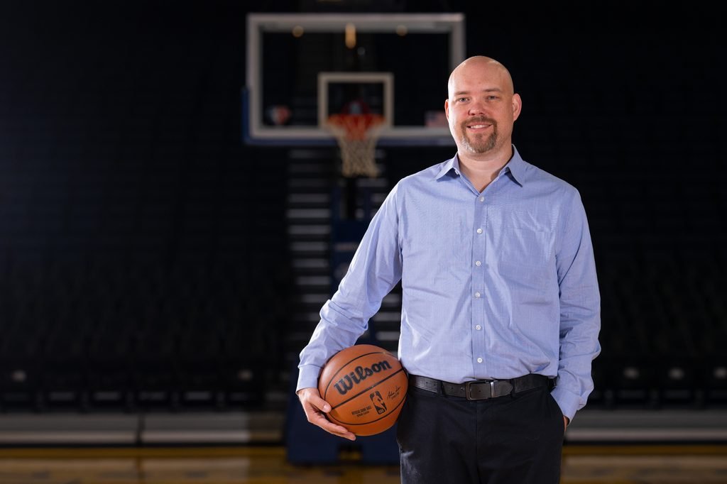 Portrait of Heitman with a basketball in hand on a basketball court. 