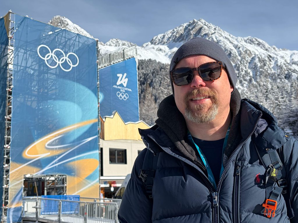 Heitman at the Olympic games with snowy mountains behind him.