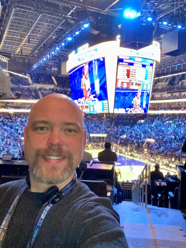 Heitman stands with a full stadium behind him during a basketball game. 